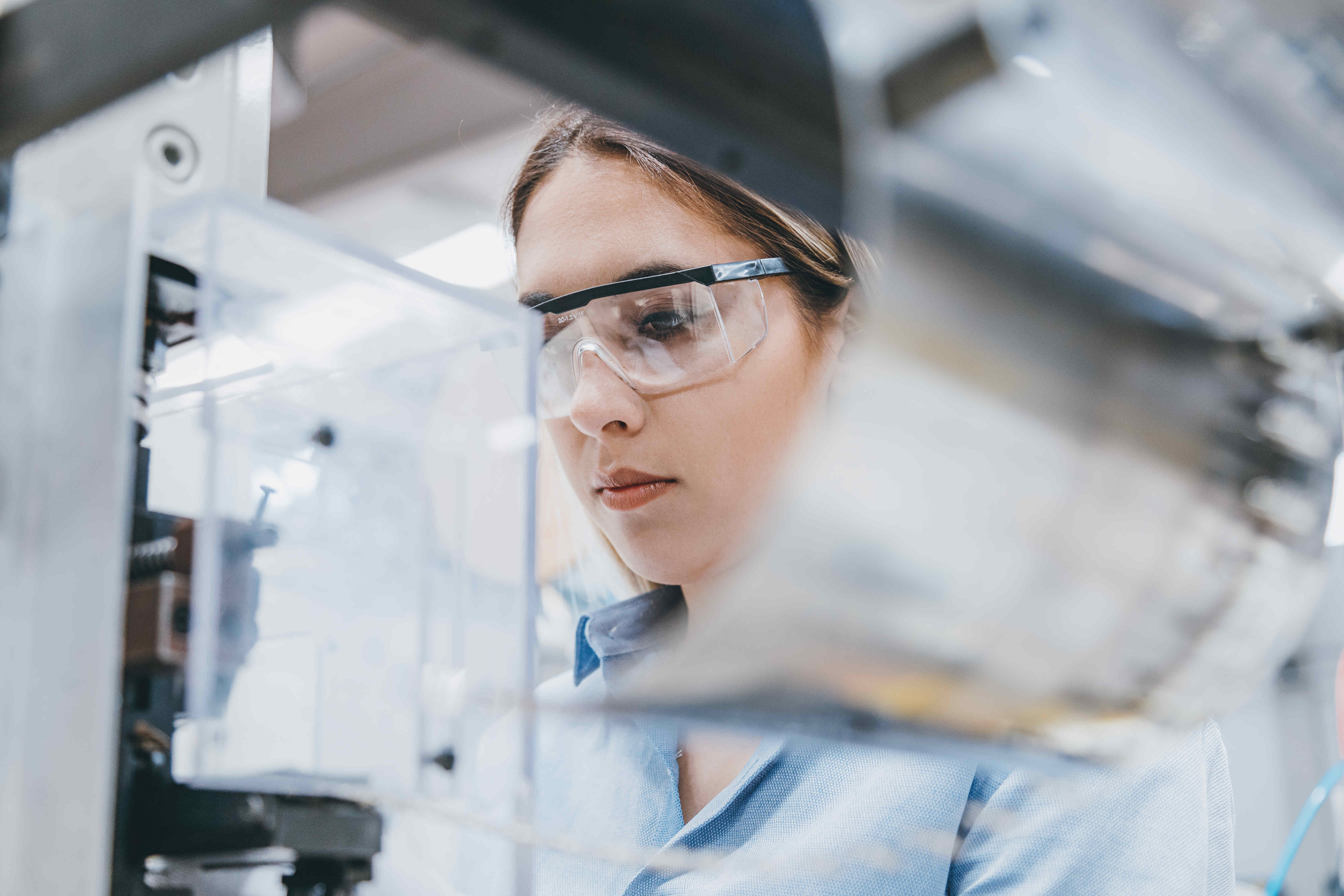 womoan in labcoat and safety glasses working in lab