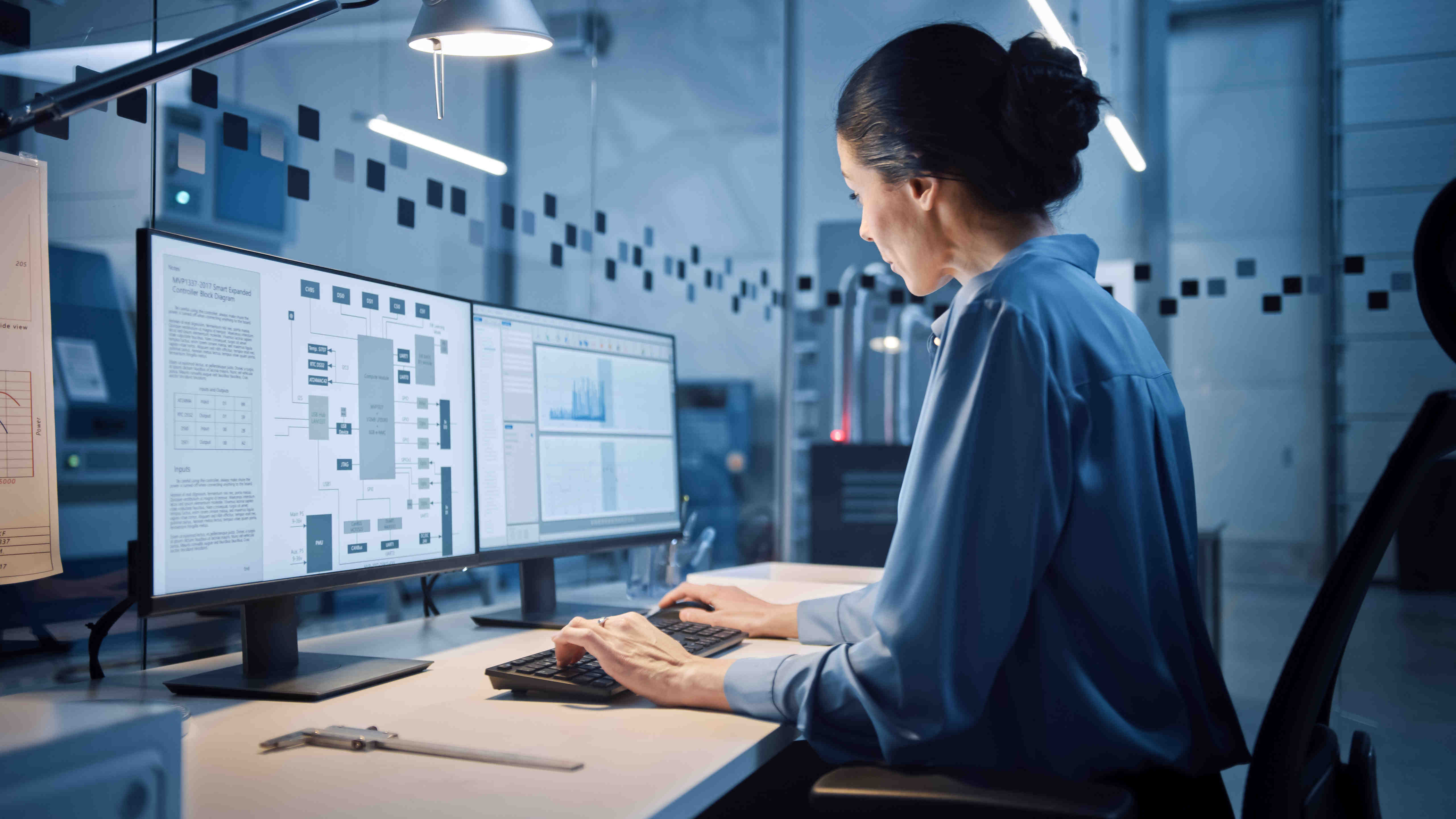 woman sitting in front of two monitors writing code