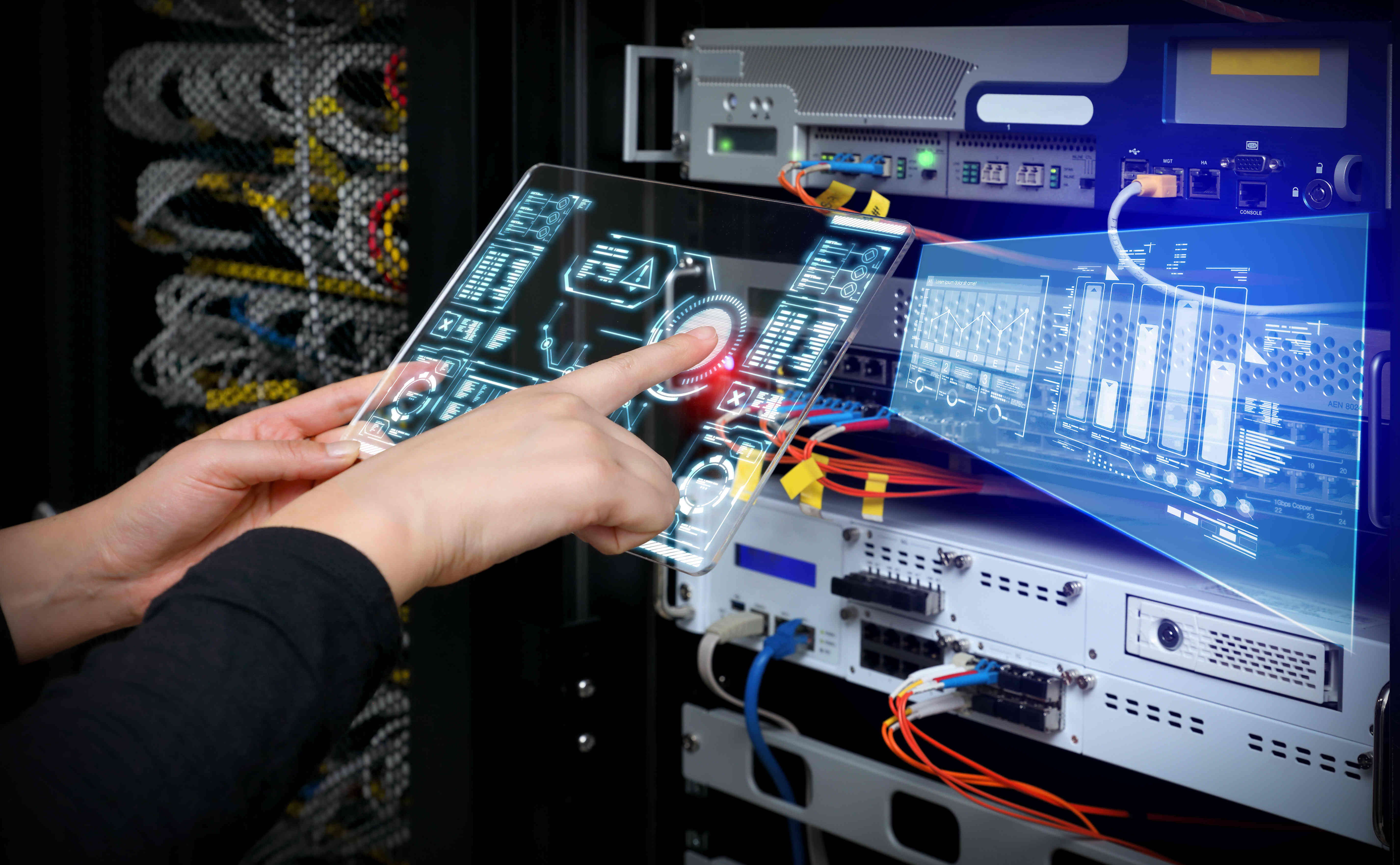 Person holding clear tablet programming while wirelessly connected to the servers they are standing in front of