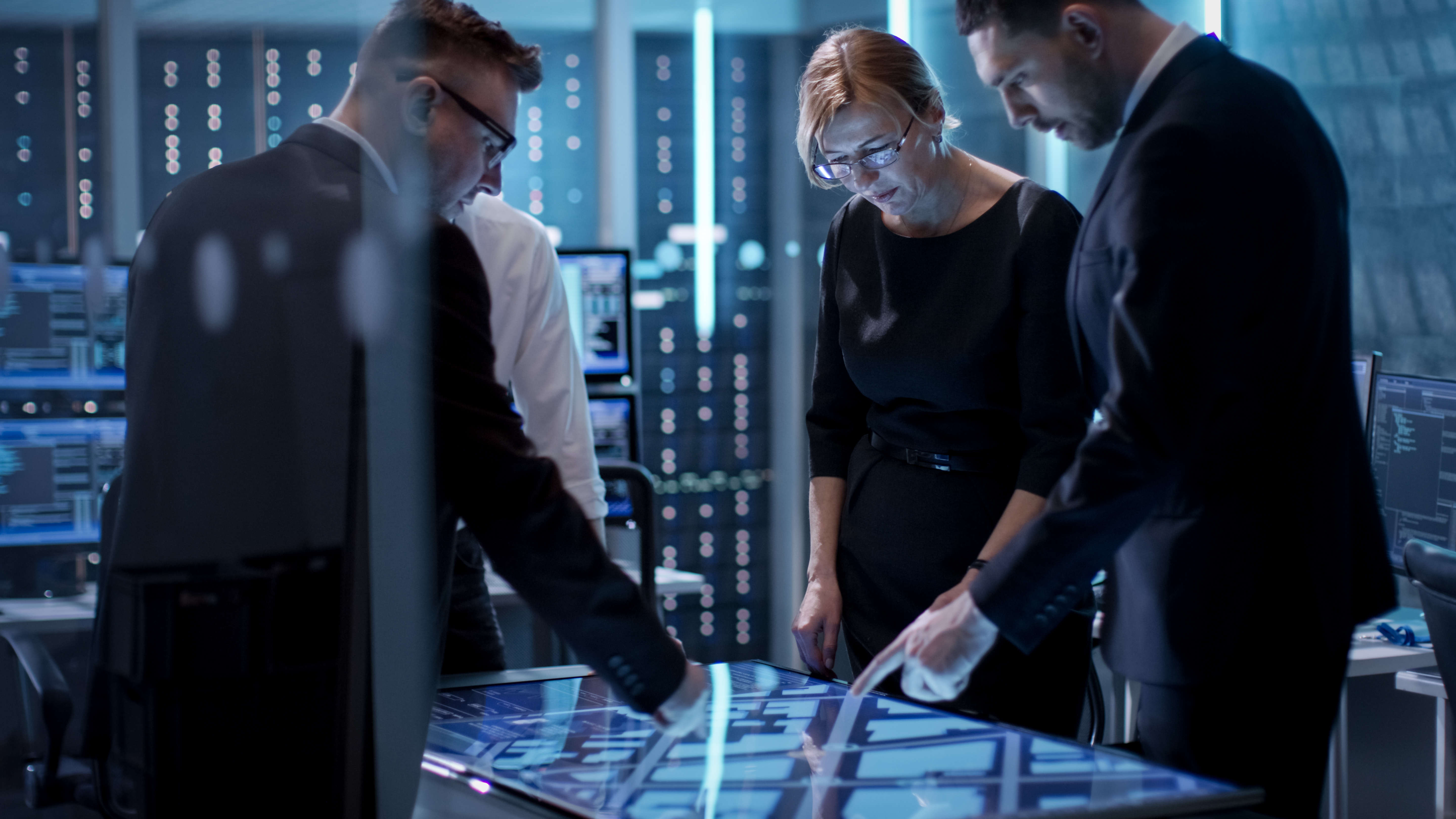 Group standing around a tabletop monitor having a discussion